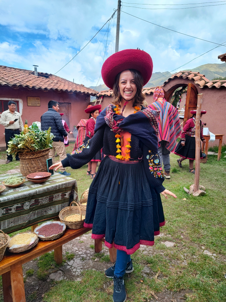 Mulher com o traje típico de Chinchero: saia de lã preta com debruns vermelhos, chapéu vermelho e casaco azul bordado