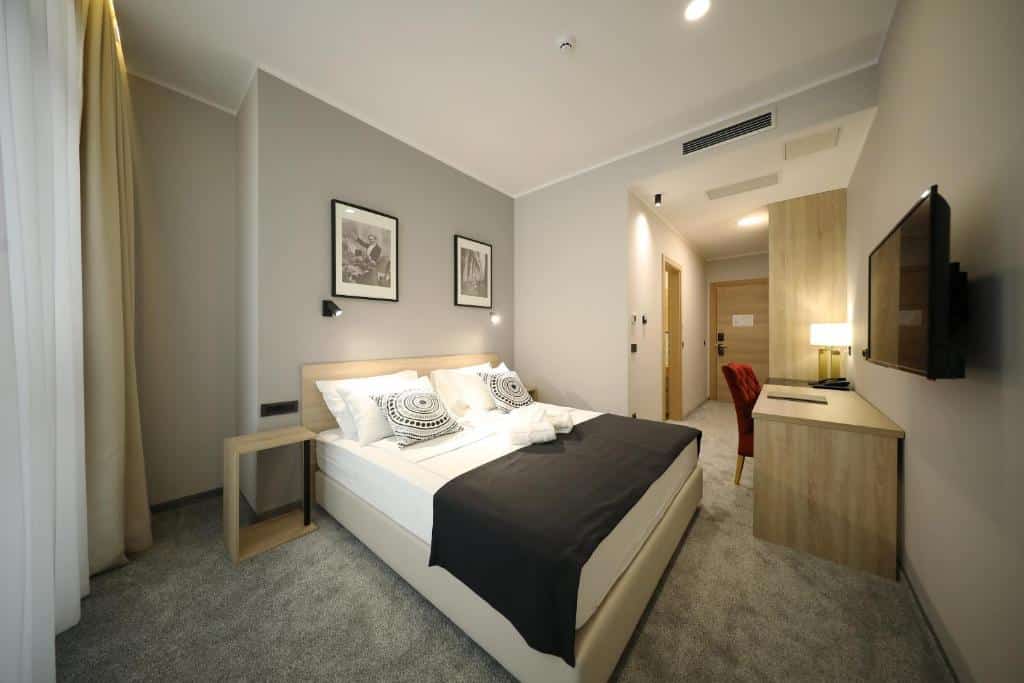 Quarto de hotel moderno com cama de casal, TV e decoração neutra, no Teatro Verdi Boutique Hotel