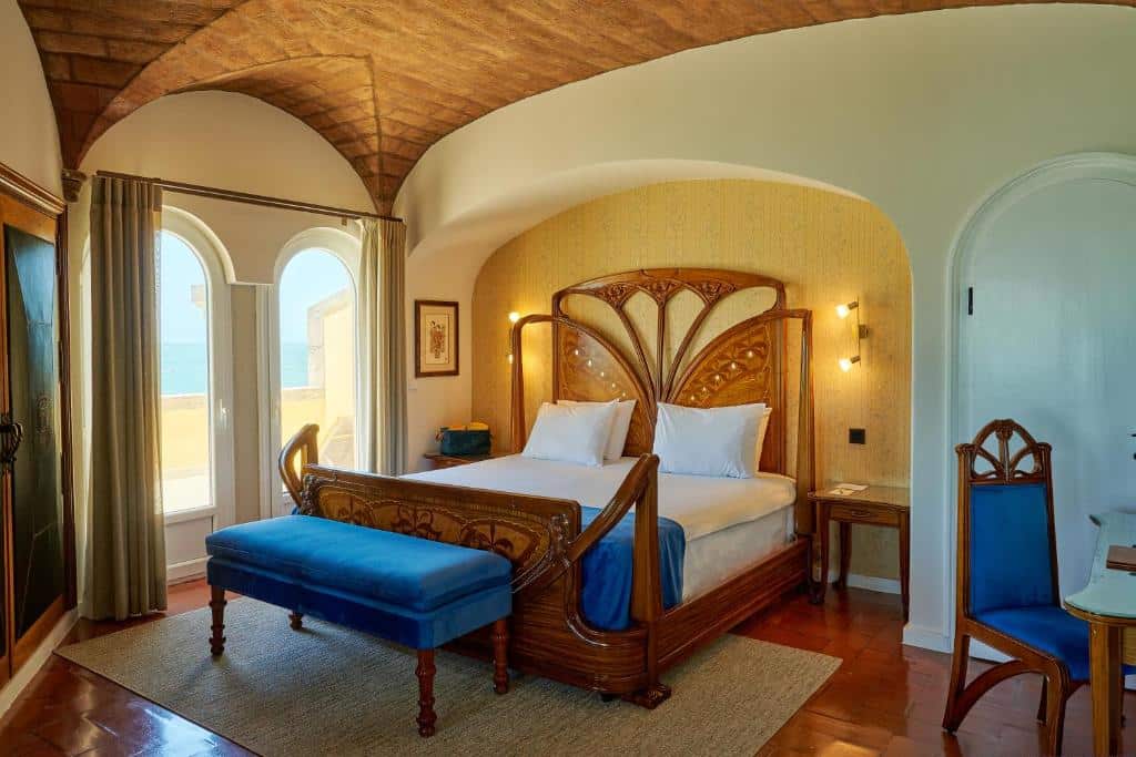 Quarto do Hotel Fortaleza do Guincho com cama de casal e porta de vidro a dar para uma varanda