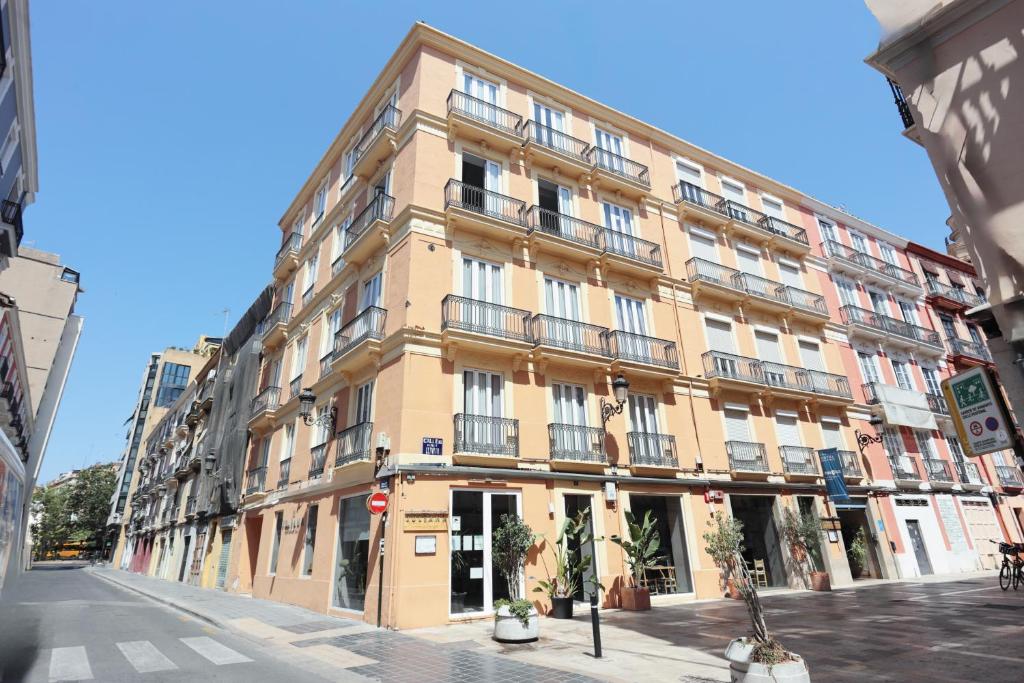 Edifício de apartamentos amarelo do YOU &amp; CO. Quart Boutique, com varandas, num centro urbano com comércio na rua.