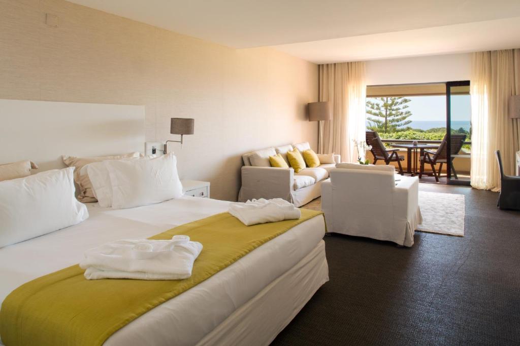 Quarto do Vilalara Thalassa Resort, com cama de casal e sala de estar com sofá e cadeirões.