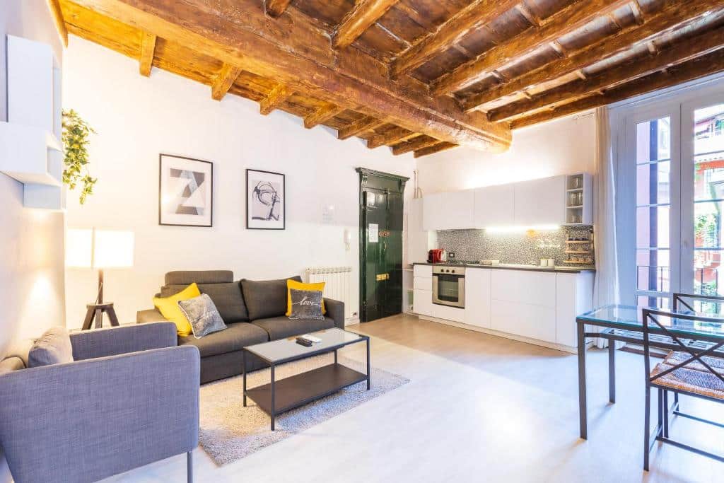Cozinha do Alzaia Naviglio Grande com uma pequena varanda, uma mesa com duas cadeiras, uma cozinha com móveis brancos, uma poltrona e um sofá de dois lugares