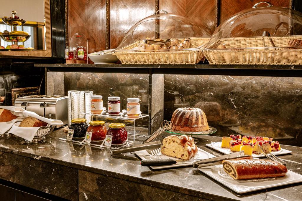 Buffet de pequeno-almoço no Hotel Erzherzog Rainer, com boiões de compota, pães, bolos, tartes, fruta cortada e cestos cobertos num balcão de mármore.