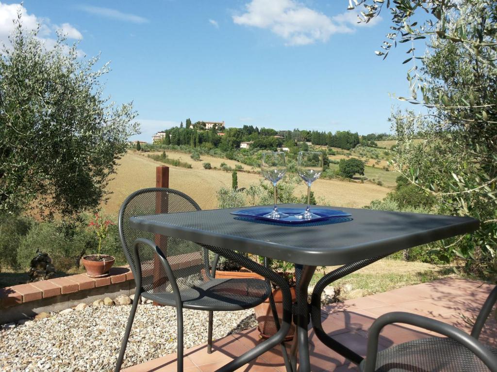 Mesa de metal com copos de vinho numa zona exterior com vista para colinas e vegetação da Toscana