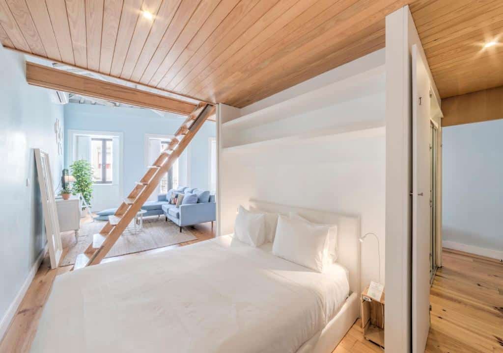 Quarto do Look At Me – Serviced Lofts & Studios, com cama de casal à direita e uma escada de madeira que dá acesso ao piso superior.