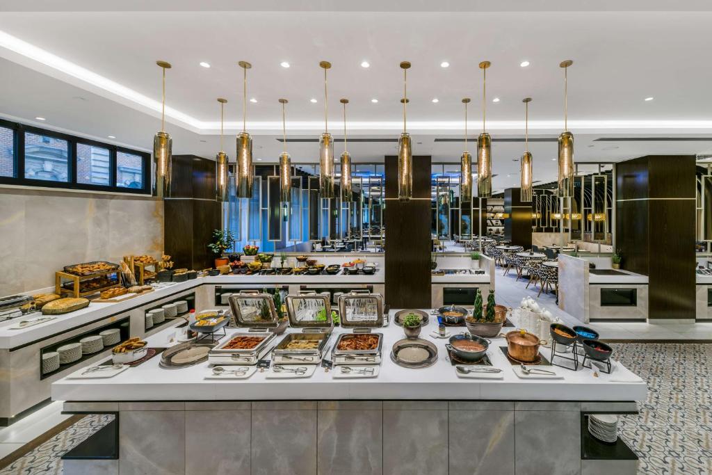 Buffet do Radisson Blu Béke Hotel numa sala de jantar moderna, com vários pratos em bandejas e candeeiros suspensos.