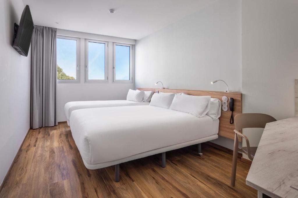 Quarto simples do B&B Hotel Lisboa Aeroporto com cama de casal e TV em frente.