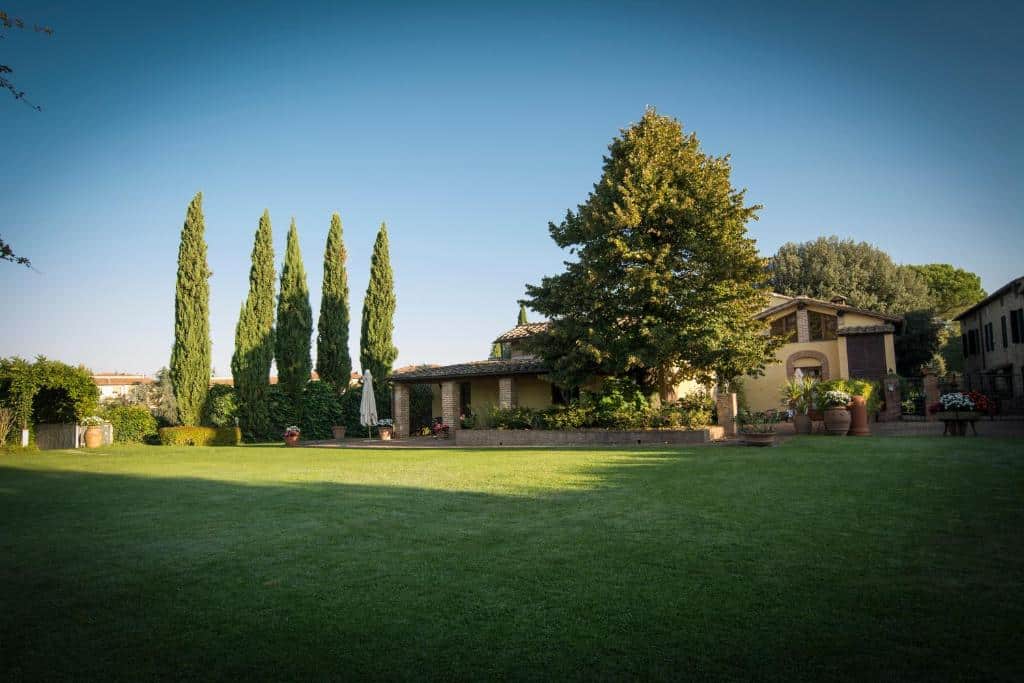 Casa de campo com jardim relvado, ciprestes e árvores na Toscana, Itália