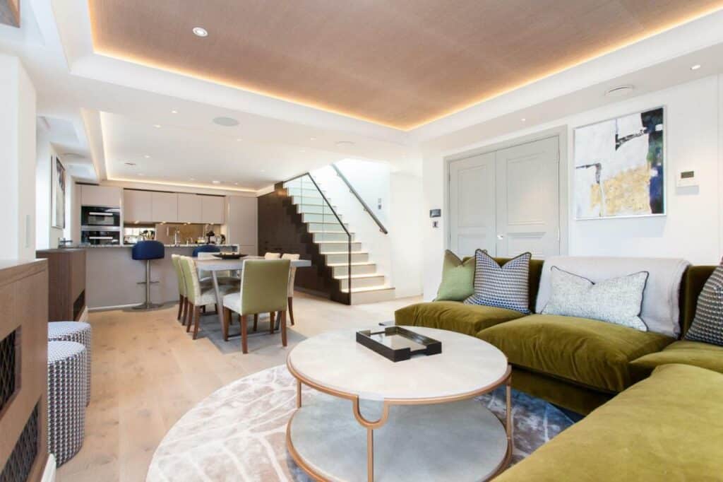 Sala do Hope House Residences by Q Apartments com cozinha partilhada e sala ampla, mesa de jantar de seis lugares, sofá em L, televisão e uma escada para o segundo andar.