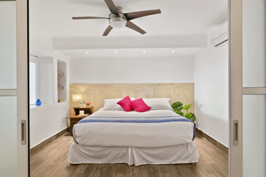 Quarto do Casa Tortugas Boutique Hotel com cama de casal ampla, prateleiras, janela, vaso de flores, chão de madeira e mesa de cabeceira com candeeiro