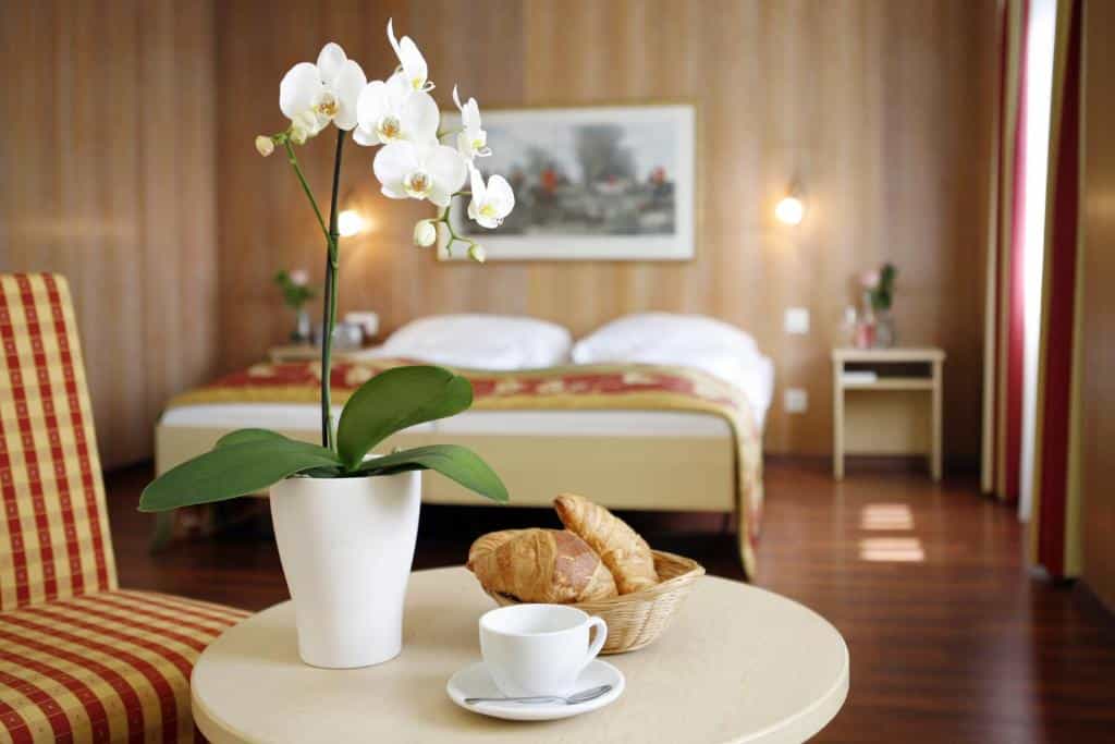 Quarto do Hotel De la Paix, em Lucerna, com mesa redonda, croissants e poltrona xadrez.