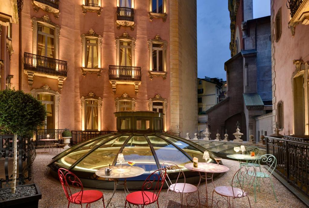 Terraço do Château Monfort com vista para os edifícios da cidade, uma abóbada de vidro ao centro e mesinhas e cadeiras coloridas em redor