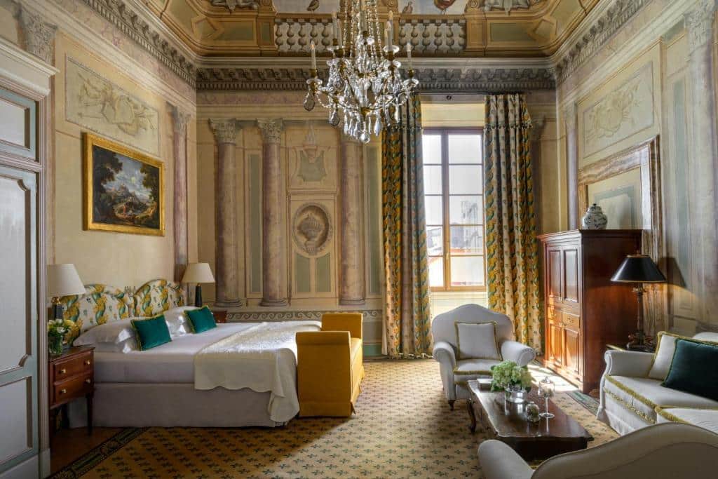 Quarto de hotel luxuoso com cama de casal, poltronas amarelas e decoração clássica em estilo europeu