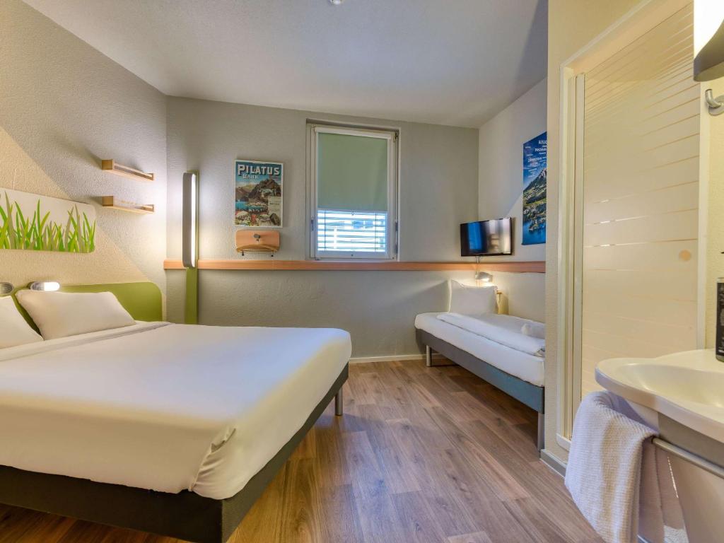 Quarto do ibis budget Hotel Luzern City, com cama de casal, roupeiro e televisão.