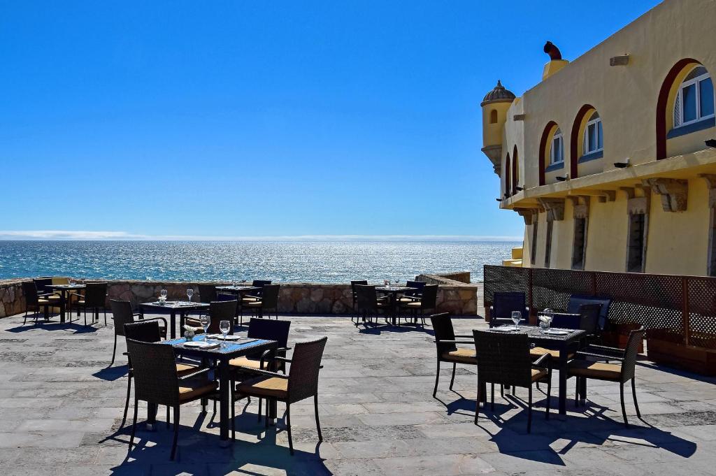 Terraço aberto com mesas e cadeiras no Hotel Fortaleza do Guincho, com uma vista incrível para o mar