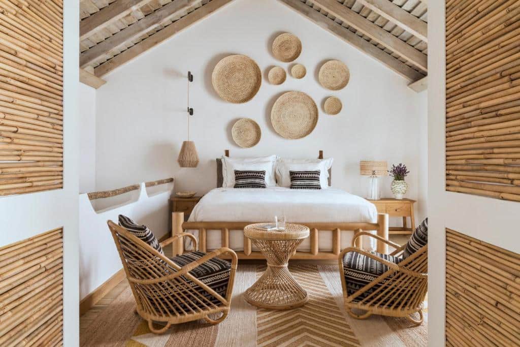 Quarto decorado com móveis de bambu e cama branca na Quinta da Comporta - Wellness Boutique Resort