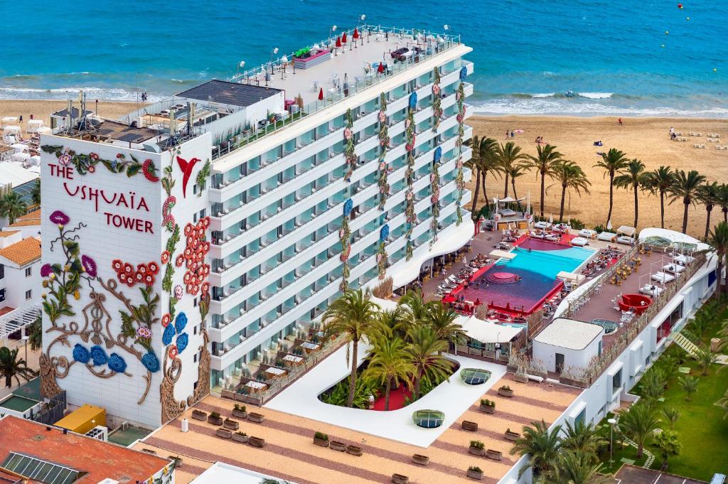 Vista aérea da The Ushuaïa Tower com piscina, palmeiras e uma praia de areia junto ao mar azul.