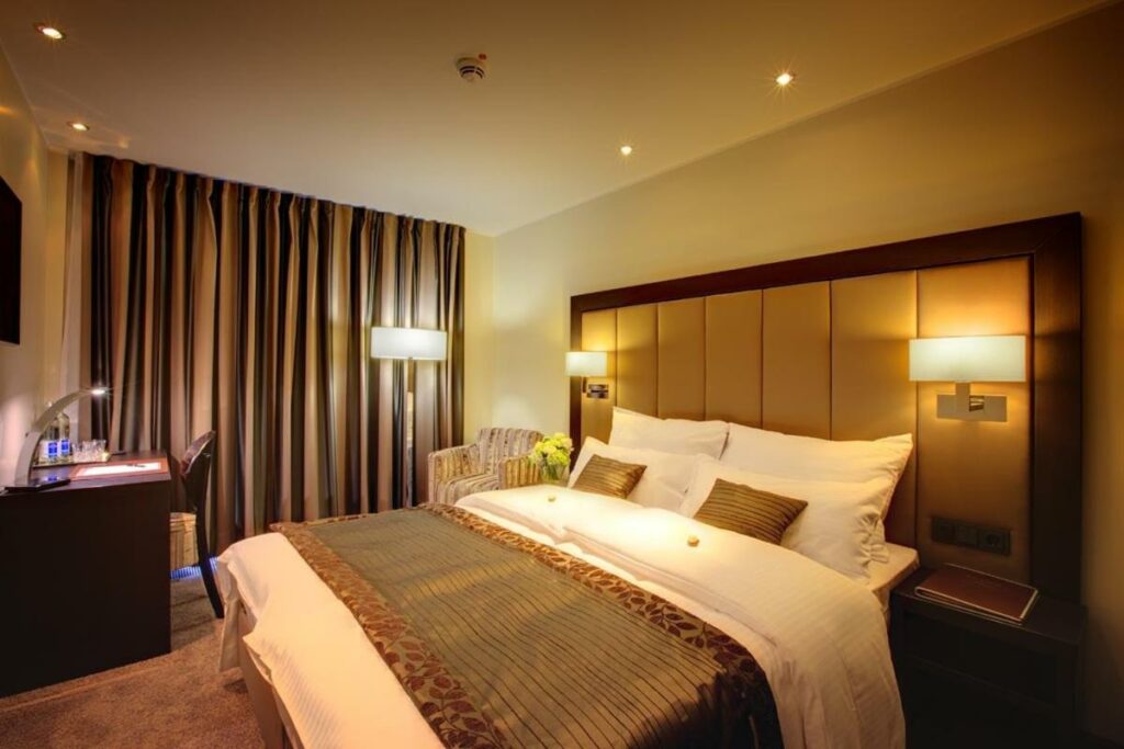 Quarto do Hotel Favor com cama de casal, poltrona e secretária de trabalho. Representa hotéis em Dusseldorf.