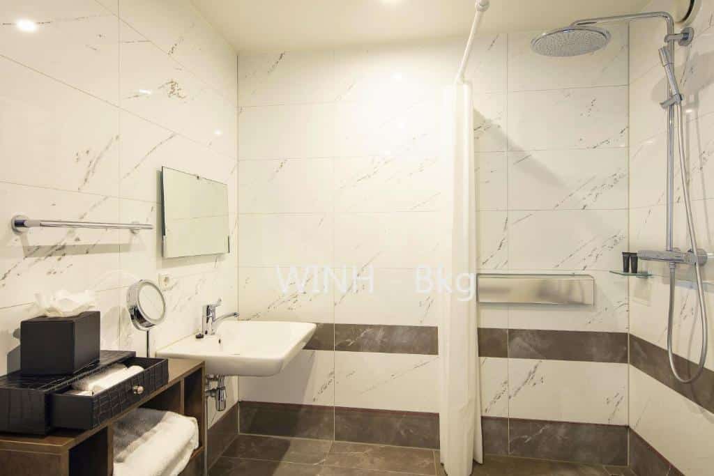 Quarto acessível do Monet Garden Hotel, de 22 m², com lavatório baixo, barras de apoio e chuveiro do lado direito, sem degraus