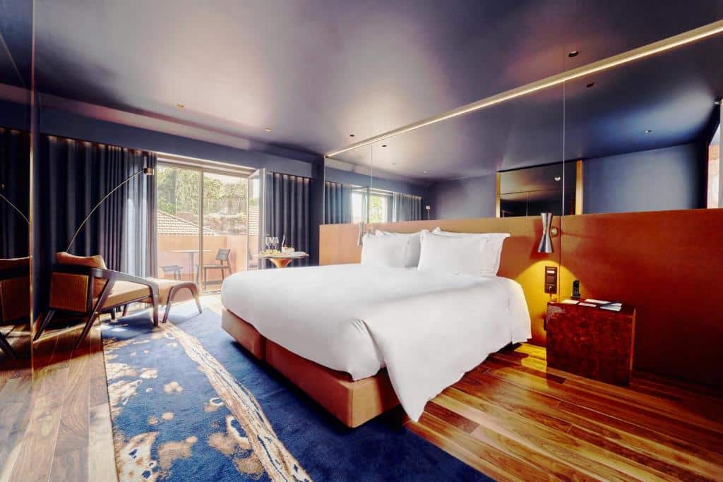 Quarto do The Lodge Porto Hotel, com cama de casal ao centro e um cadeirão.