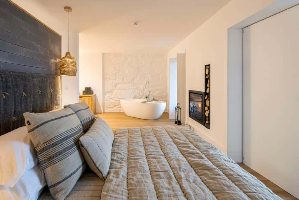 Quarto do TheVagar Countryhouse com cama de casal, lareira e banheira de hidromassagem.