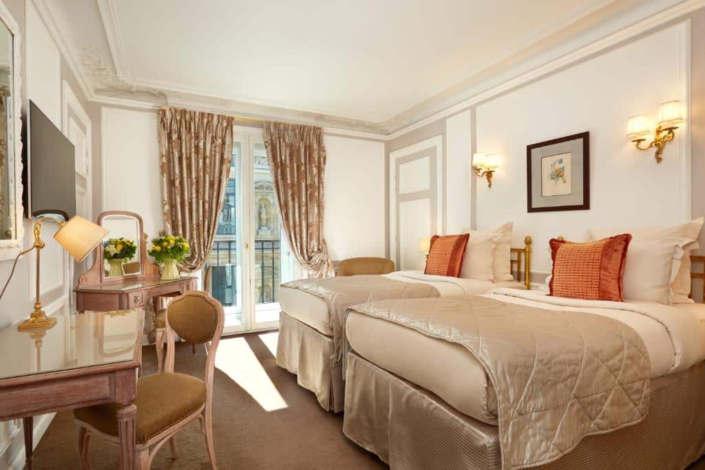 Quarto do Hôtel Regina Louvre com duas camas individuais, uma secretária com cadeira, uma TV, luminárias de parede e uma janela com cortinas.