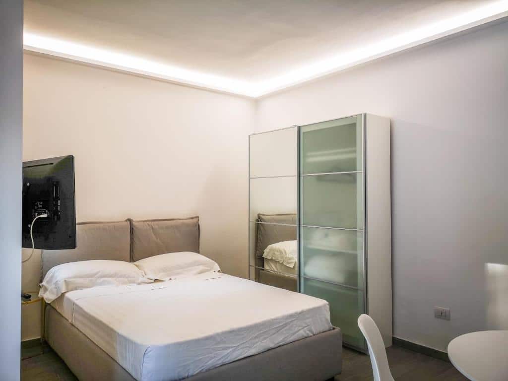 Quarto do Riama Agriresort com cama de casal, armário de vidro e televisão na parede.