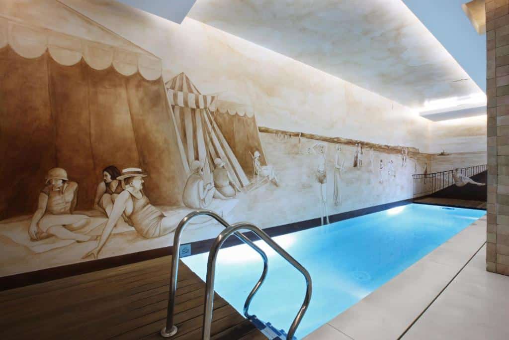 Pequena piscina interior do Heritage Avenida Liberdade, com uma parede pintada com uma cena de pessoas numa praia