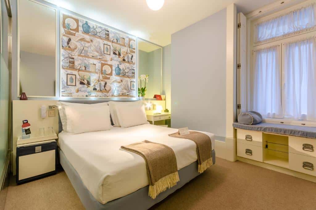 Cama de casal bem arrumada com roupa de cama branca, mantas castanhas e arte decorativa na parede, num quarto moderno e bem iluminado, no Lx Boutique Hotel.