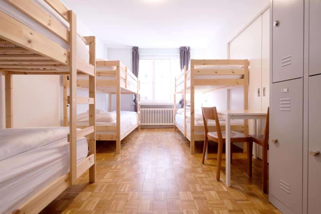 Quarto do Barabas Luzern, com três beliches, mesa com cadeiras e cacifo com cadeado.
