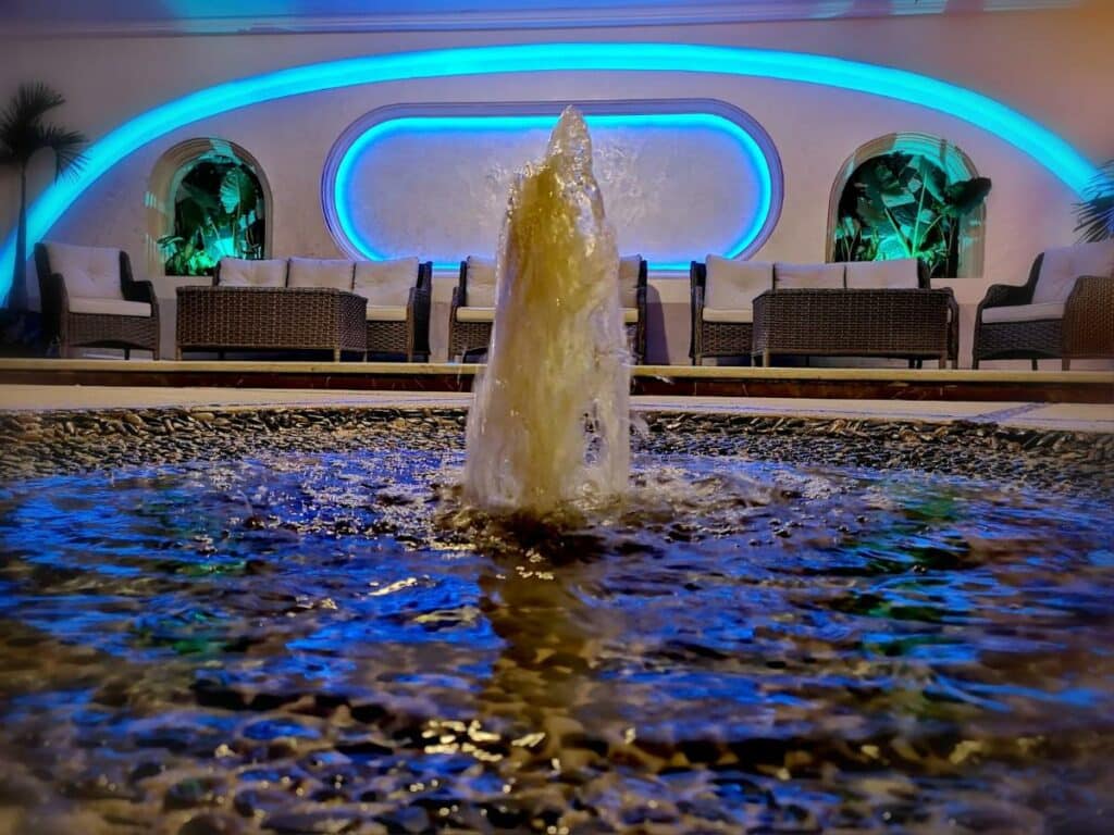 Piscina no Hotel Blue Star Cancun com deck rodeado de sofás e iluminação azul
