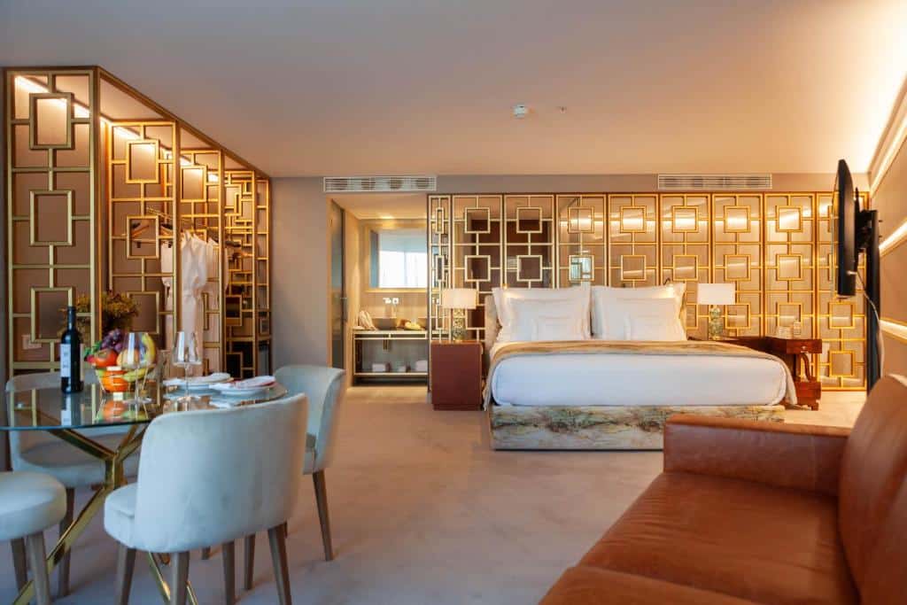 Quarto amplo do Wine & Books Lisboa Hotel com cama de casal, sofá, televisão e mesa com fruta e vinho