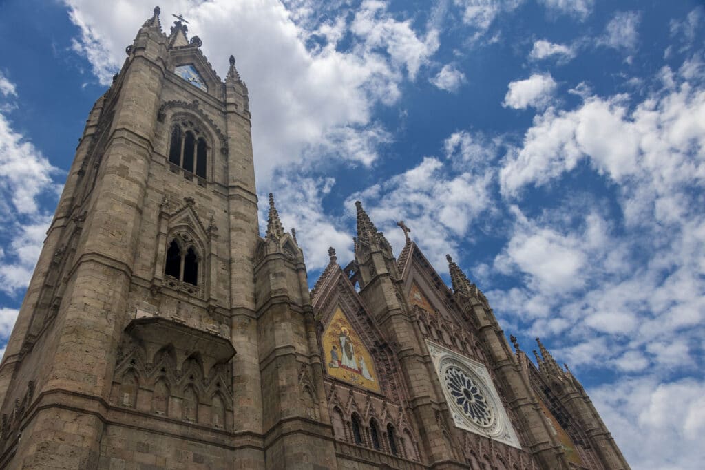 Templo Expiatório do Santíssimo Sacramento, imponente templo neogótico com torres pontiagudas e elementos arquitetónicos detalhados em fachada de pedra contra céu azul nublado.