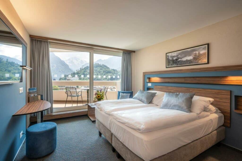 Quarto do Metropole Swiss Quality Hotel com cama de casal, poltrona e porta para a varanda.
