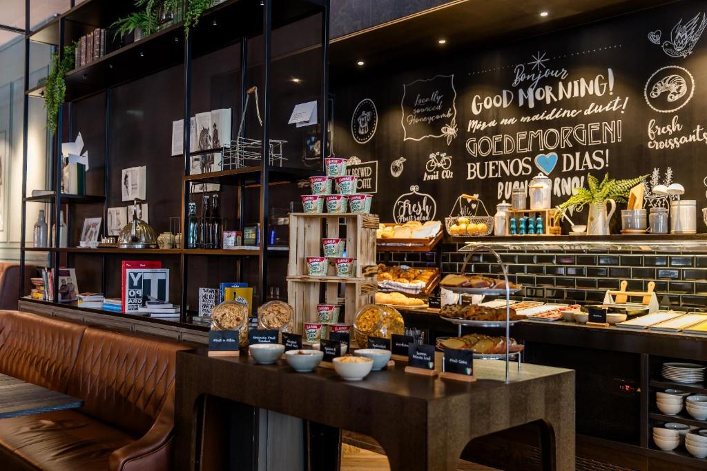 Cafetaria no Motel One Dublin com decoração rústica e elementos naturais. Balcão de pedra com variedade de produtos de pastelaria e bebidas em copos e embalagens personalizados.