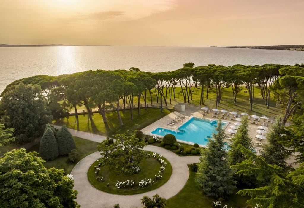 Piscina de hotel com vista para o mar, espreguiçadeiras e jardim com pinheiros na orla, no Falkensteiner Hotel Adriana l Adults Only (Borik)