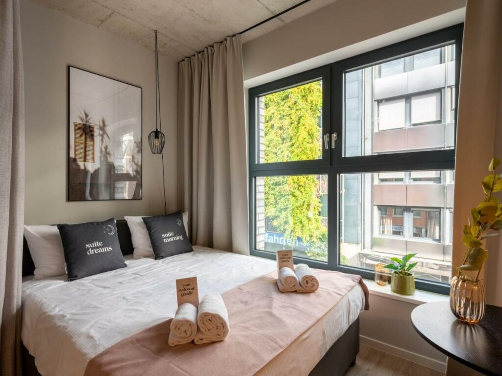 Quarto do limehome Düsseldorf Stresemannstraße com cama de casal e mesa redonda. Representa hotéis em Dusseldorf.