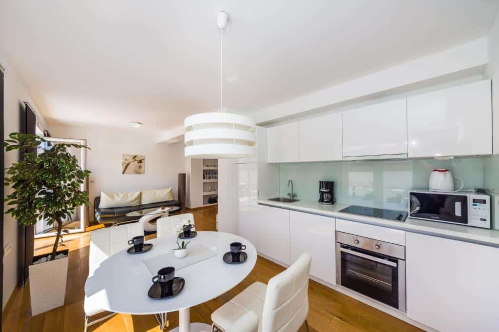 Cozinha aberta planeada branca com mesa redonda e cadeiras em apartamento moderno, na Villa Zadar Superior, em Diklo