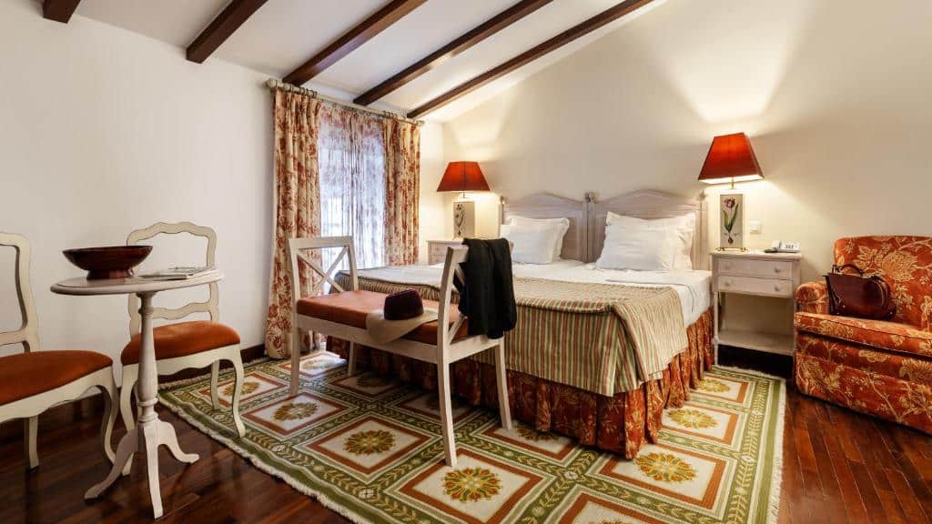 Quarto aconchegante com cama de casal e poltrona na Pousada de Marvão
