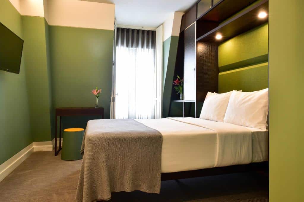 Quarto do My Story Hotel Augusta com uma cama de casal e uma janela com cortinas, uma televisão em frente à cama, uma pequena mesa e uma pufe verde