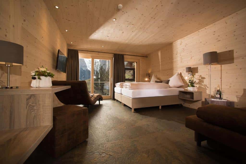 Quarto do Hotel Silberhorn, com sofá, cama de casal, poltrona e porta de vidro para a varanda.