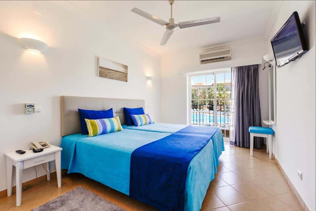 Quarto do 3HB Clube Humbria – All Inclusive com cama de casal do lado esquerdo uma cômoda com telefone do lado esquerdo da cama. Representa hotéis all inclusive em Portugal.
