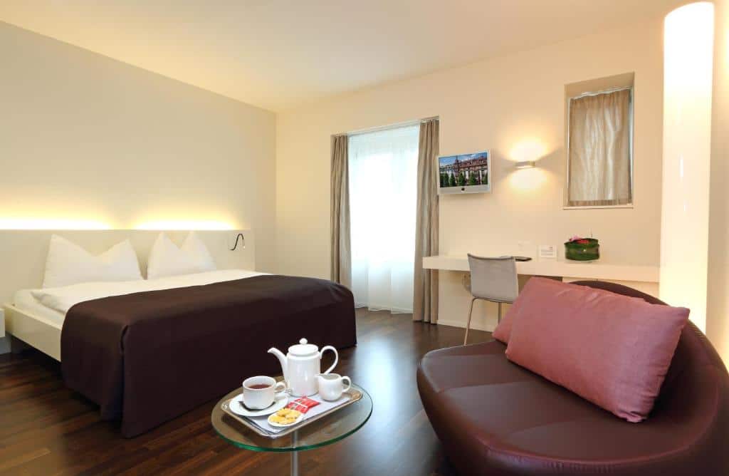 Quarto do Waldstätterhof Swiss Quality Hotel, com cama de casal, poltrona de couro e secretária.