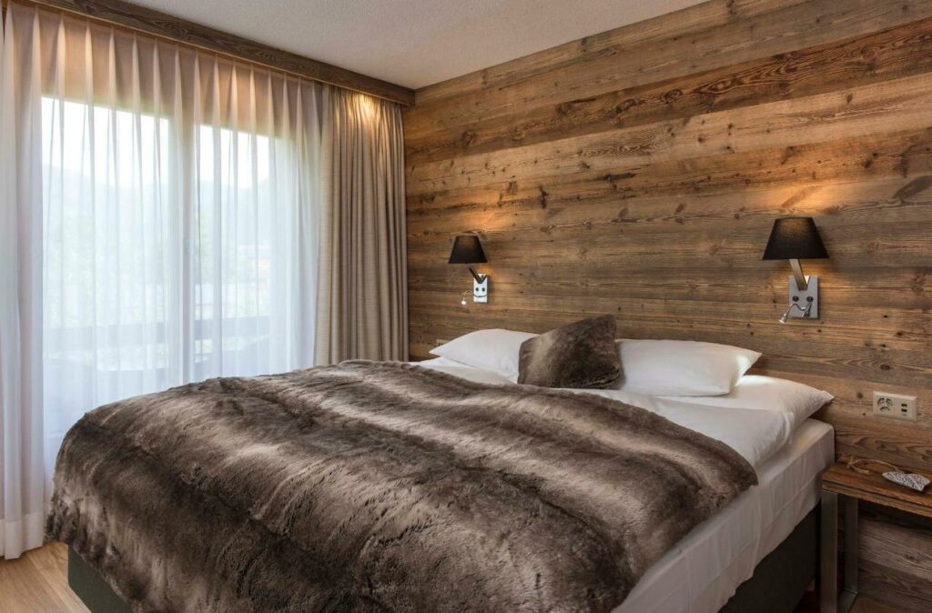 Quarto do Salzano Hotel com cama de casal e janelas com cortinas.