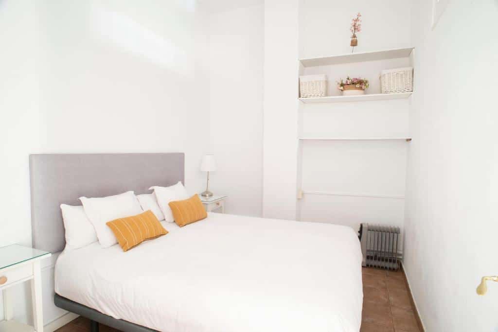 Quarto acolhedor do ABCyou Bed&amp;Breakfast, com cama de casal, cabeceira cinzenta, almofadas amarelas e prateleiras brancas com cestos na parede.