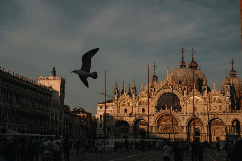 Basílica de São Marcos com pombos a voar, na Praça de São Marcos, Veneza, Itália