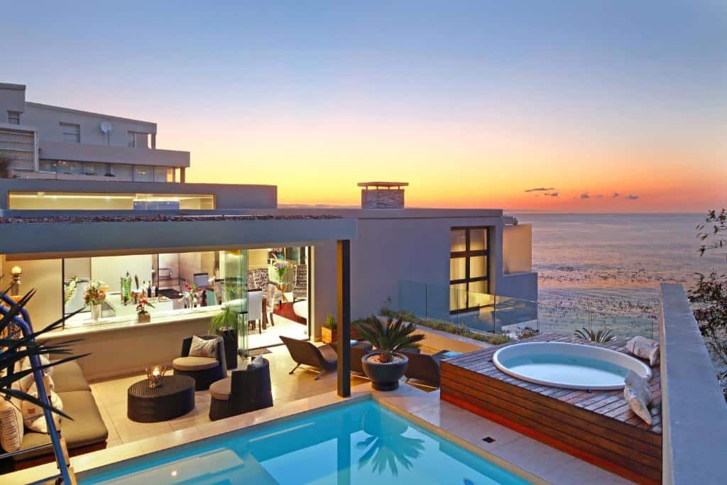 Azamare Guest House com piscina exterior, jacúzi e zona de estar com vista para o oceano ao pôr do sol.