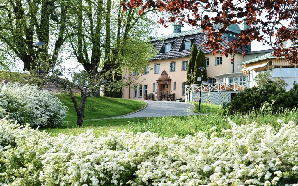 Fachada do Såstaholm Hotell & Konferens com jardim florido e árvores.