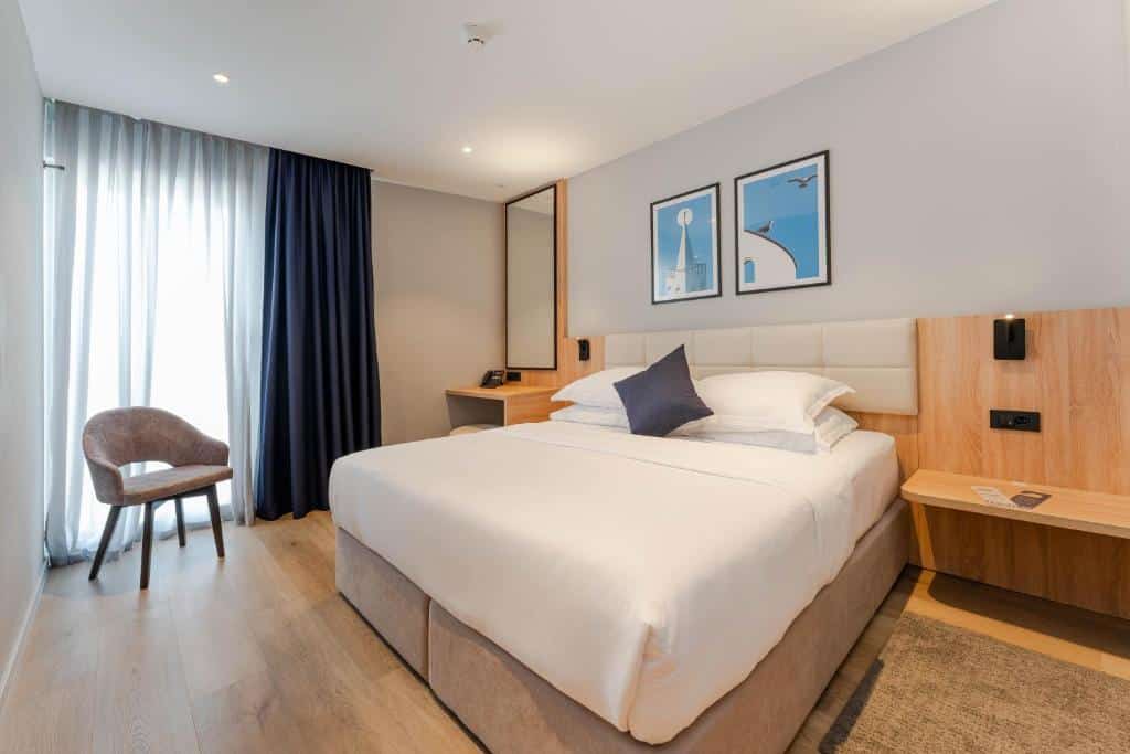 Quarto de hotel moderno com cama de casal, mesa de cabeceira e poltrona num ambiente claro, no Hotel A’mare, no Centro de Zadar