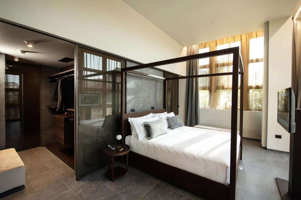 Quarto do Gold Tower Lifestyle Hotel com cama de dossel, armário e janelas com vista para o exterior.
